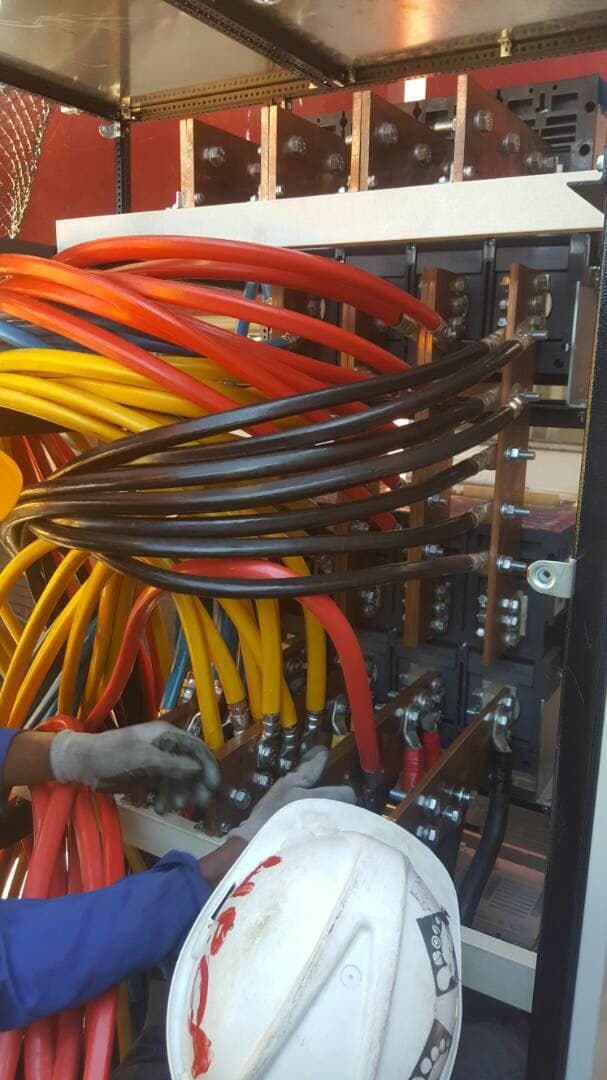 An electrician terminating heavy multi-core cables onto a busbar inside a distribution panel