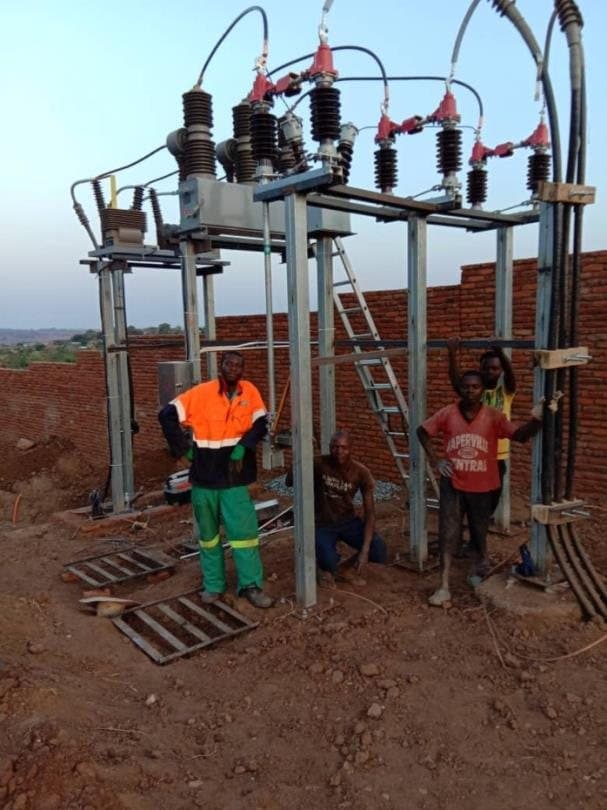 A crew working at an outdoor substation structure with red insulators