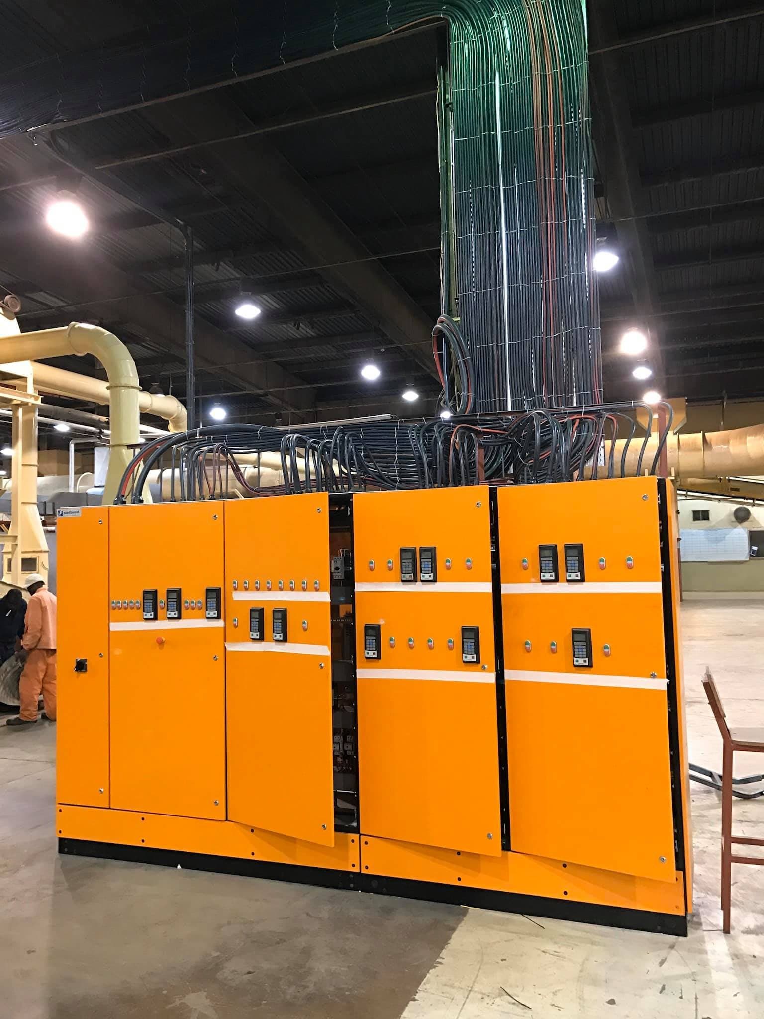 A lineup of switchboards installed in a plant, with cable drops overhead