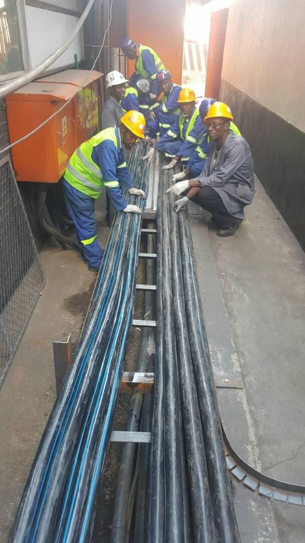 A team pulling cables onto ladder tray in a floor duct
