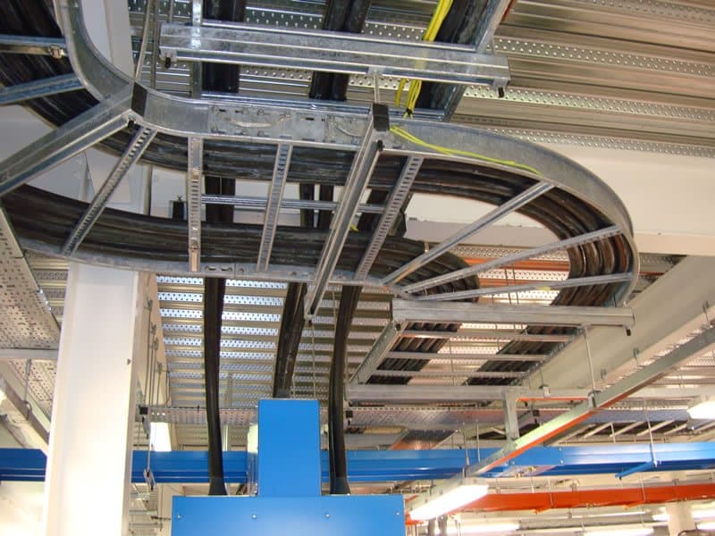 A curved cable tray run carried under a factory roof