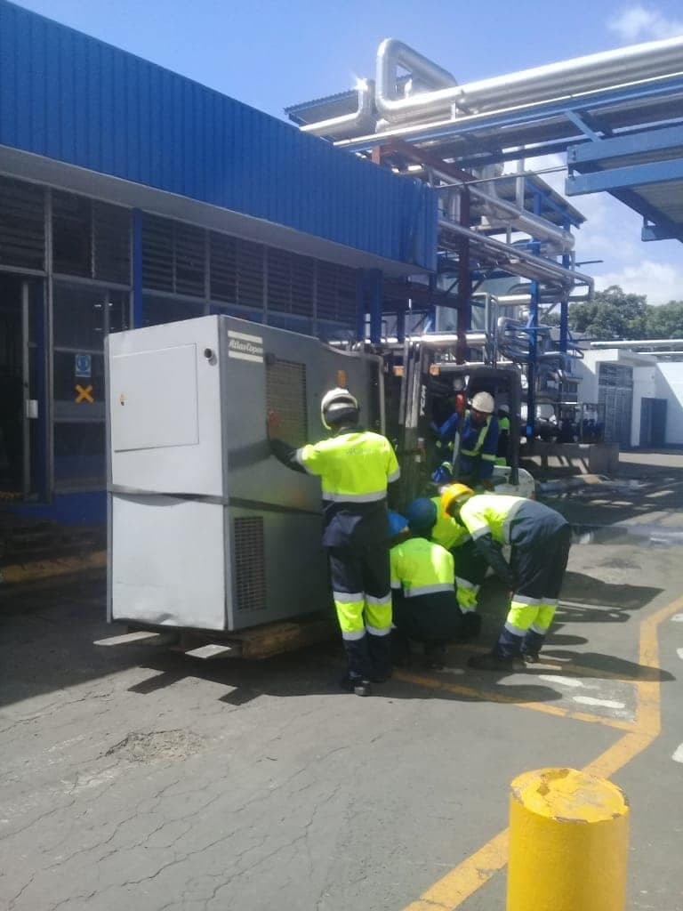 A crew manoeuvring a control panel into position outside a plant