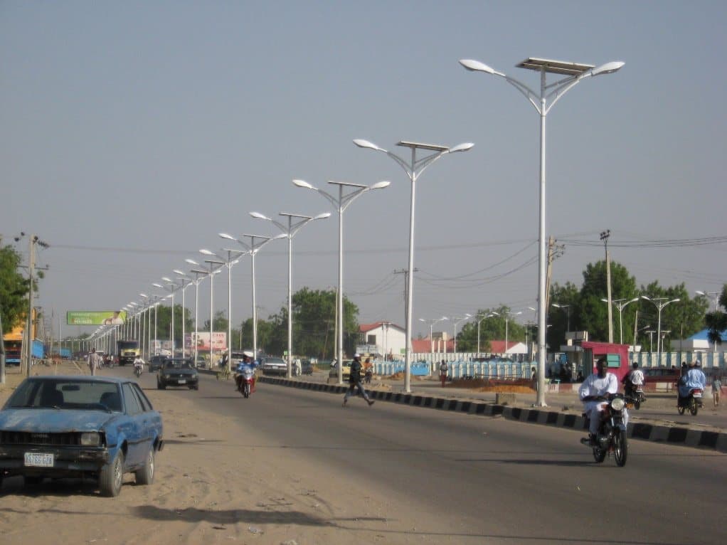 A dual carriageway lined with installed street lighting, in daylight