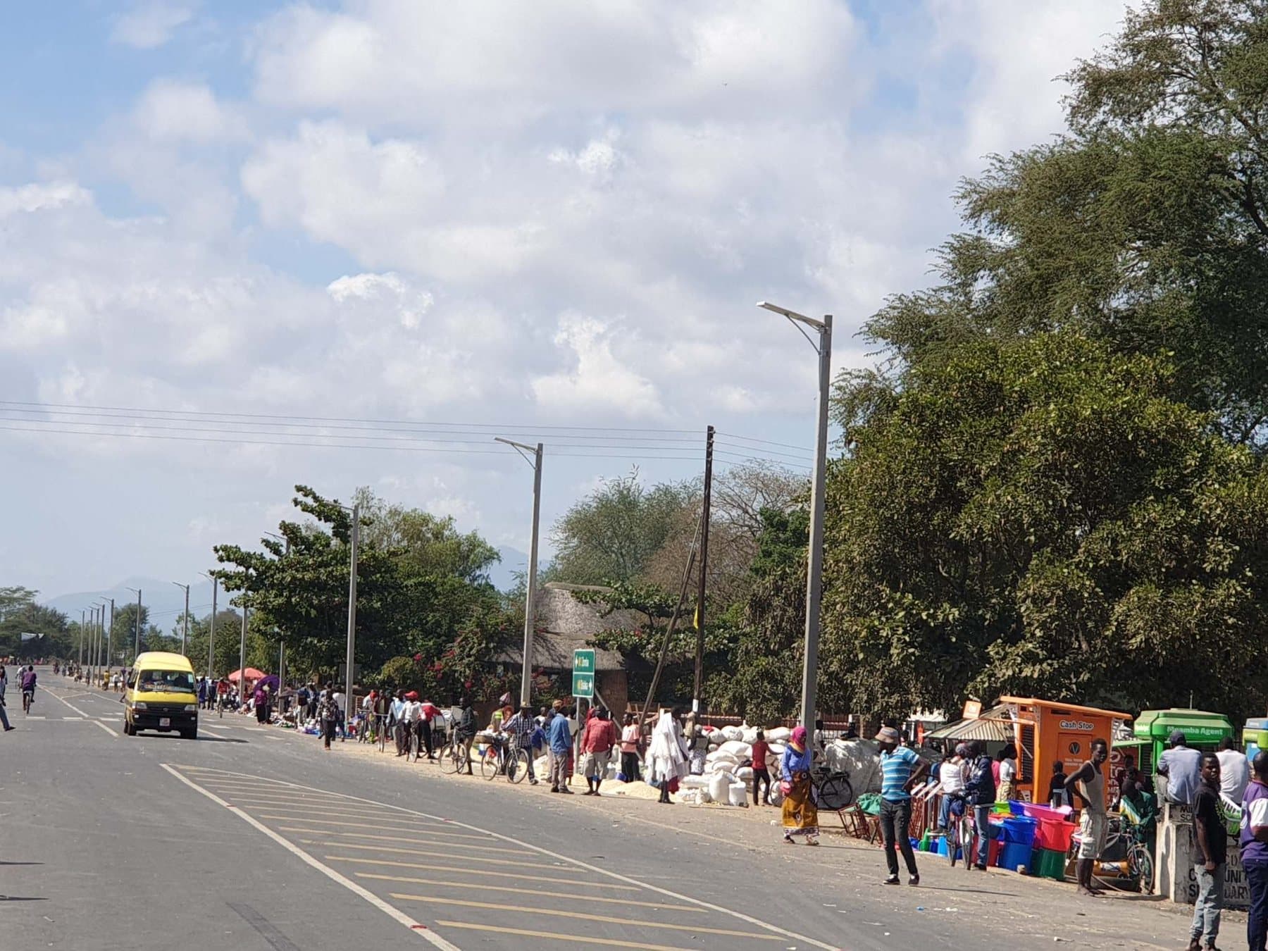 Street lighting along a town road busy with traders and pedestrians